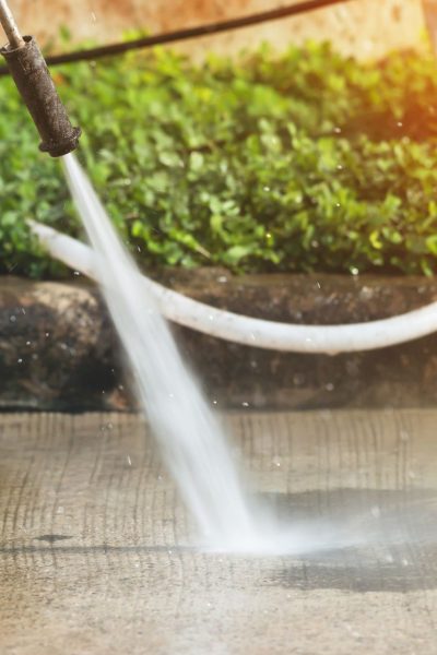 person-wearing-rainboots-pressure-washing-driveway-aeeec933df5148afa57457d6d1fe6aea